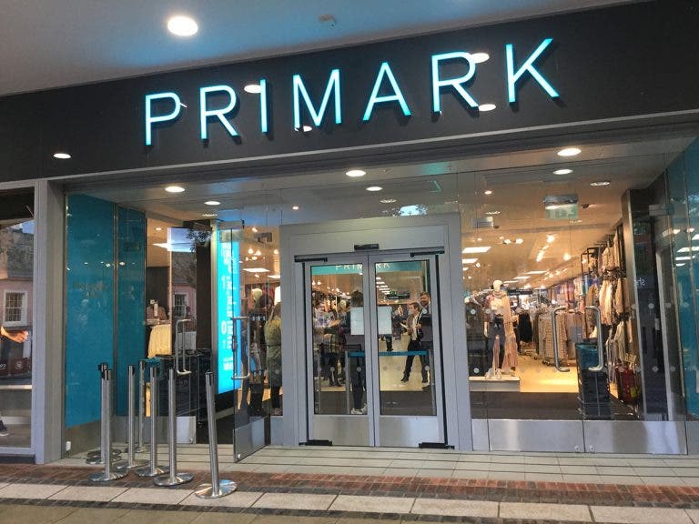 Fachada del establecimiento Primark, resaltando su moderno diseño y sus escaparates de moda, con una falda Primark de tendencia en la vitrina.