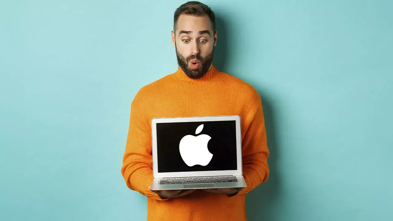 Modelo vestido de naranja sosteniendo una Mac, simbolizando la unión de Orange y Apple.