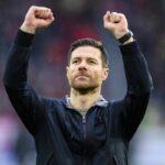 Xabi Alonso aplaudiendo a la grada durante un partido, con el escudo del Liverpool proyectado.
