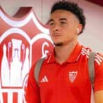 Rubén Vargas con polo rojo del Sevilla FC y auriculares puestos entrando en las instalaciones del club en febrero de 2026.