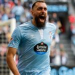 Borja Iglesias celebrando un gol con la boca abierta y gesto eufórico, vistiendo una camiseta azul claro de su equipo actual.