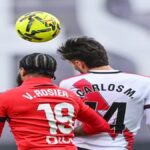 Osasuna asalta Vallecas ante Rayo Vallecano en LaLiga EA Sports con un triunfo decidido en el añadido Un partido igualado durante muchos minutos se resolvió por eficacia visitante y gestión emocional en el tramo final El duelo en Vallecas dejó una lectura clara sobre competitividad y gestión de finales de partido. Osasuna golpeó cuando más duele y se llevó tres puntos de enorme valor. El Rayo Vallecano dominó la posesión durante muchos tramos, pero no tradujo ese control en ventaja real. El encuentro se mantuvo abierto hasta el último suspiro. La eficacia navarra fue determinante. El marcador no refleja todo lo ocurrido sobre el césped. Osasuna golpea primero y castiga la falta de contundencia local tras un inicio con dominio territorial del Rayo El arranque fue de iniciativa local, con el Rayo Vallecano tratando de instalarse en campo rival mediante posesiones largas. Sin embargo, el primer golpe llegó del lado visitante. En el minuto 29, Ante Budimir aprovechó una acción bien trabajada para adelantar a Osasuna, culminando una asistencia precisa de Herrando. El tanto asentó al conjunto rojillo, que supo bajar el ritmo del partido y gestionar los espacios. El Rayo mantuvo el balón, pero le costó generar ocasiones claras ante una defensa bien organizada. La primera parte se cerró con sensación de control visitante pese al empuje local. Tras el descanso, el escenario cambió. El Rayo subió líneas y encontró premio en el minuto 60. Pathé Ciss firmó el empate tras una acción colectiva bien interpretada, con Isi Palazón como asistente. Vallecas empujó y el partido entró en una fase de intercambio de golpes y tensión creciente. El tramo final y el VAR marcan el desenlace con dos goles tardíos que sellan la victoria rojilla Cuando el empate parecía definitivo, Osasuna mostró mayor claridad emocional. En el minuto 91, Víctor Muñoz apareció para firmar el 1 a 2 tras una jugada rápida que castigó el desajuste local. El Rayo acusó el golpe y dejó espacios en su intento desesperado por igualar. Poco después llegó la acción más controvertida. El VAR revisó una posible pena máxima a favor de Osasuna, pero el árbitro mantuvo su decisión inicial. Esa revisión alargó el añadido y terminó beneficiando de nuevo a los visitantes. En el minuto 94, Asier Osambela sentenció el partido con el tercer tanto. La acción fue validada tras una nueva revisión del VAR, confirmando un desenlace cruel para el Rayo y muy rentable para Osasuna. Lectura competitiva y consecuencias clasificatorias tras un partido de dos caras bien diferenciadas El Rayo Vallecano cerró el partido con un 67 por ciento de posesión, dato que refuerza su propuesta pero también expone su falta de pegada. Osasuna, por su parte, demostró colmillo competitivo y capacidad para decidir en escenarios de máxima presión. La victoria refuerza al conjunto navarro en la clasificación y consolida su fiabilidad como visitante. Para el Rayo, el resultado deja la sensación de oportunidad perdida y la necesidad de ajustar detalles en los minutos decisivos. En partidos tan ajustados, la eficacia vuelve a marcar la diferencia. V. Rosier y Carlos M. saltando por un balón aéreo en un lance del partido entre el Rayo Vallecano y el CA Osasuna en Vallecas.