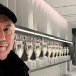 Carlo Ancelotti posando con las Champions del Madrid, reflejando su estatus de técnico de élite.