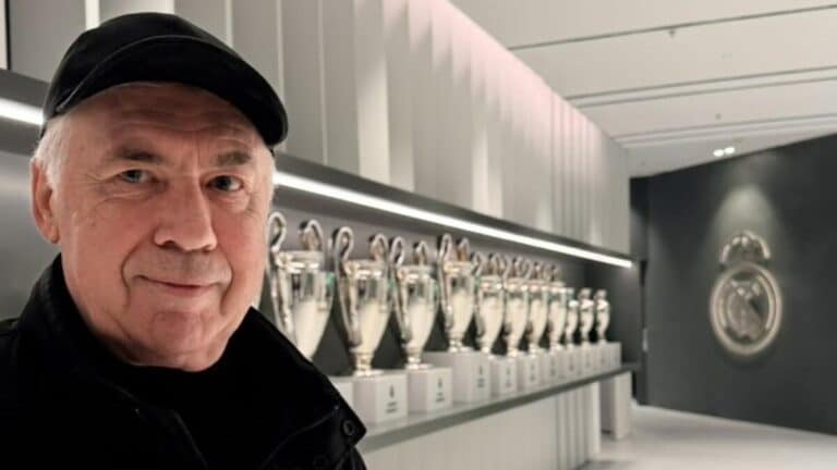 Carlo Ancelotti posando con las Champions del Madrid, reflejando su estatus de técnico de élite.