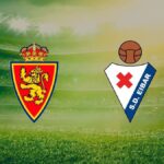 Escudos del Real Zaragoza y la SD Eibar sobre el césped de un estadio de fútbol para el partido de LaLiga Hypermotion
