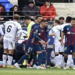 Primer plano del árbitro Saúl Ais Reig con el silbato en la boca durante un partido de la Liga Hypermotion en febrero de 2026.