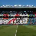 Estadio de fútbol con un mosaico de colores blanco, rojo y azul realizado por los aficionados en las gradas.