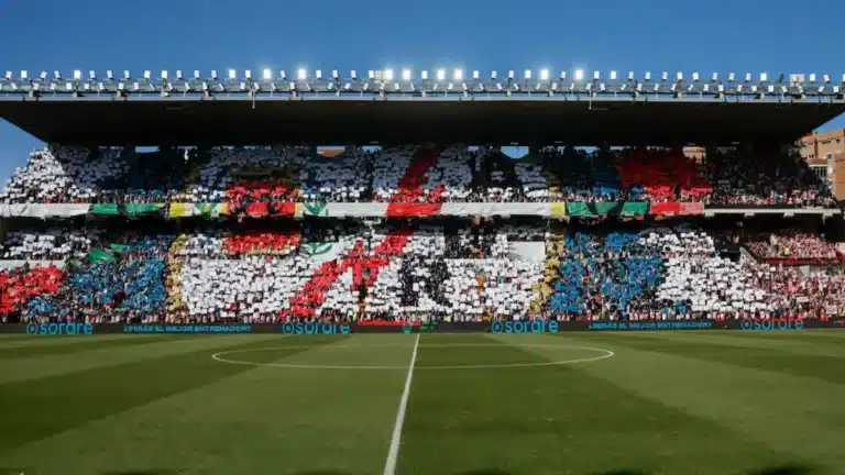 Estadio de fútbol con un mosaico de colores blanco, rojo y azul realizado por los aficionados en las gradas.