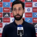 Álvaro Arbeloa hablando en zona mixta frente a un panel de patrocinadores del Real Madrid como Emirates, Mahou y HP.