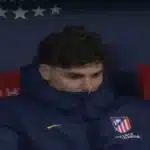 Julián Álvarez cabizbajo en el banquillo del Atlético de Madrid, reflejando su falta de compromiso y motivación.