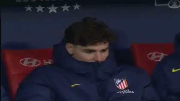 Julián Álvarez cabizbajo en el banquillo del Atlético de Madrid, reflejando su falta de compromiso y motivación.