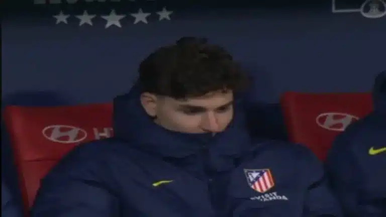 Julián Álvarez cabizbajo en el banquillo del Atlético de Madrid, reflejando su falta de compromiso y motivación.