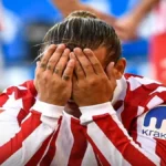 Primer plano de un jugador del Atlético de Madrid con la camiseta rojiblanca tapándose la cara con ambas manos en un gesto de absoluta frustración tras la derrota ante el Rayo Vallecano.