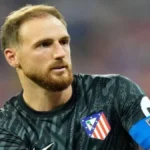 Jan Oblak, portero del Atlético de Madrid con barba y el brazalete de capitán azul, mirando fijamente con gesto serio durante el partido ante el Rayo Vallecano.