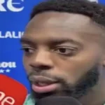 Primer plano de Iñaki Williams, delantero y capitán del Athletic Club con barba corta, hablando seriamente ante un micrófono de RNE tras la victoria ante el Real Oviedo.