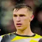 Nico Schlotterbeck, central del Borussia Dortmund, señalando con el dedo durante un partido bajo la lluvia.