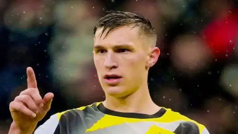 Nico Schlotterbeck, central del Borussia Dortmund, señalando con el dedo durante un partido bajo la lluvia.