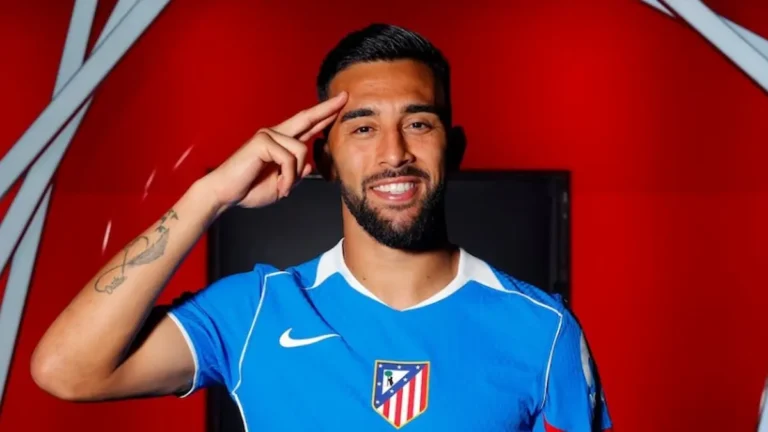 Nico González posando con la camiseta azul del Atlético de Madrid y haciendo un gesto de saludo con la mano en la frente.