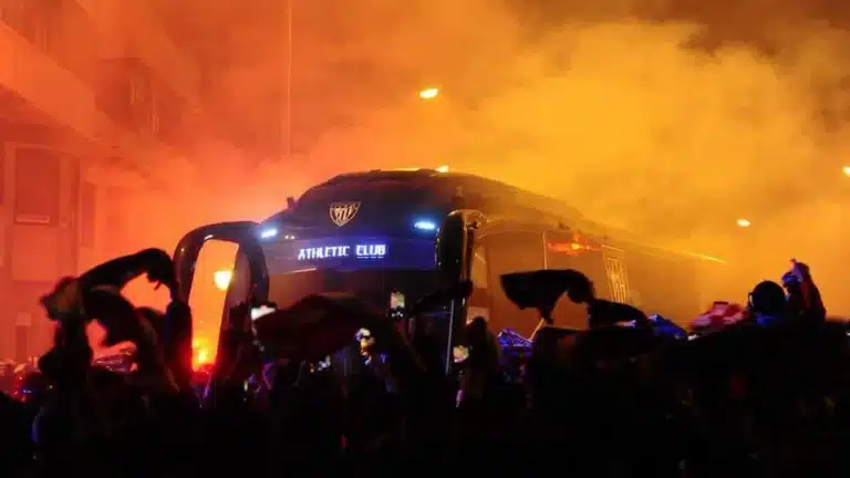 Miles de aficionados del Athletic Club rodeando el autobús del equipo con bengalas rojas y humo en los prolegómenos de un partido en San Mamés.