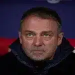 Primer plano del entrenador Hansi Flick con gesto serio y pensativo durante un partido del FC Barcelona.