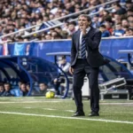 Guillermo Almada, entrenador del Real Oviedo, con traje oscuro, gritando y gesticulando con la mano en la boca desde la banda durante el partido contra el Athletic Club.