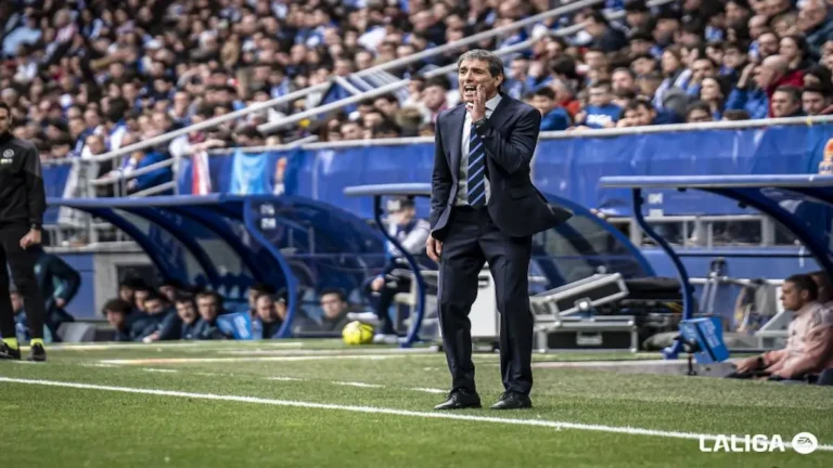 Guillermo Almada, entrenador del Real Oviedo, con traje oscuro, gritando y gesticulando con la mano en la boca desde la banda durante el partido contra el Athletic Club.