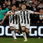 Dos jugadores del CD Castellón con la equipación albinegra a rayas verticales celebran un gol con los brazos extendidos y gestos de alegría sobre el césped del SkyFi Castalia.
