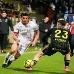 Acción de juego entre un jugador de la Cultural Leonesa con camiseta blanca 'Aspire' y un jugador del Real Zaragoza con el dorsal 23 'Cuenca' durante el partido en el Reino de León.
