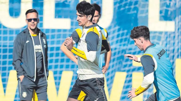 Gerard Moreno realizando ejercicios de estiramiento durante un entrenamiento del Villarreal CF bajo la supervisión médica.