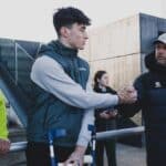 Manex Lozano, con muletas, saluda al entrenador del Racing José Alberto López tras confirmarse su grave lesión de rodilla.