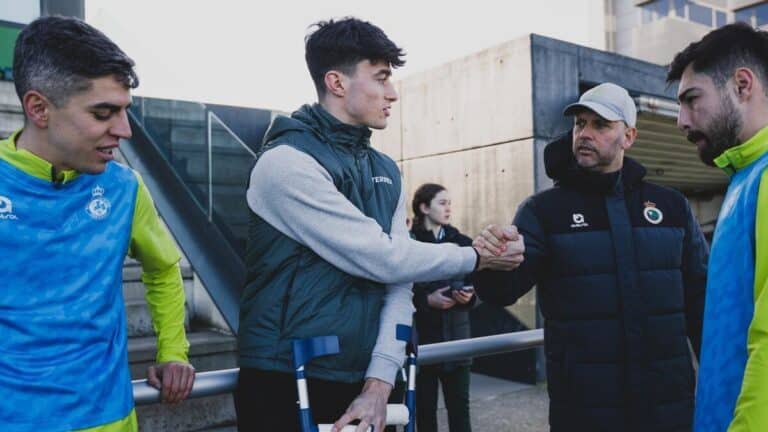 Manex Lozano, con muletas, saluda al entrenador del Racing José Alberto López tras confirmarse su grave lesión de rodilla.