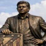 Montaje de una estatua de bronce de Mateu Alemany junto al escudo del Atlético de Madrid frente al estadio.