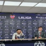 Carlos Corberán, entrenador del Valencia CF con chaqueta oscura, gesticulando con las manos mientras da instrucciones desde la banda en el Ciutat de València.
