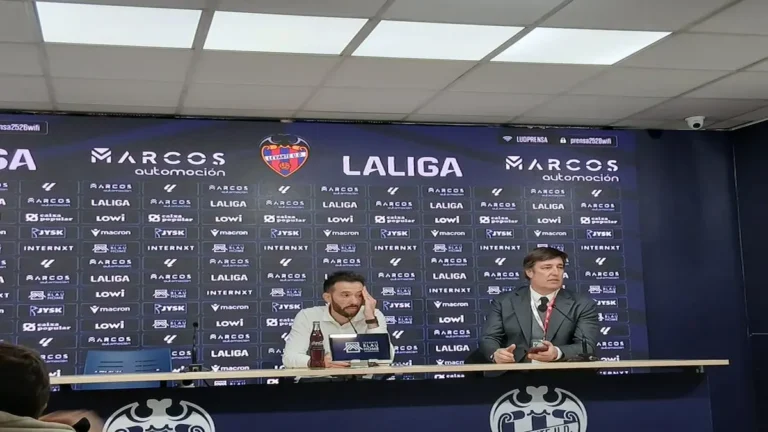Carlos Corberán, entrenador del Valencia CF con chaqueta oscura, gesticulando con las manos mientras da instrucciones desde la banda en el Ciutat de València.