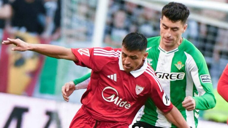 Jugador del Sevilla con camiseta roja disputa un balón con un defensor del Betis con camiseta verde y blanca durante el derbi de La Cartuja en LaLiga