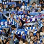 Aficionados de la Real Sociedad animando en Anoeta con banderas y bufandas antes del viaje a la final de Copa en Sevilla, marzo de 2026.