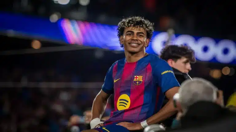 Lamine Yamal sonriendo en el banquillo del FC Barcelona durante un partido de Champions League
