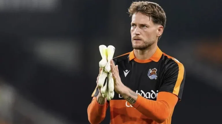 Álex Remiro aplaudiendo con la camiseta naranja de portero de la Real Sociedad al finalizar un partido