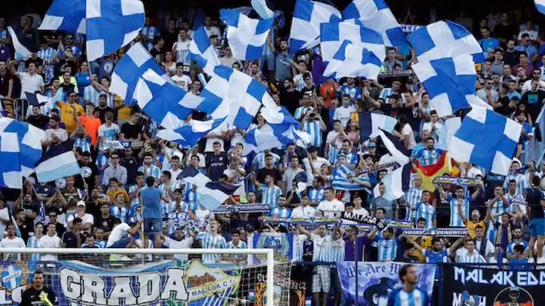 Afición del Málaga CF en La Rosaleda ondeando banderas azules y blancas en un partido de playoff
