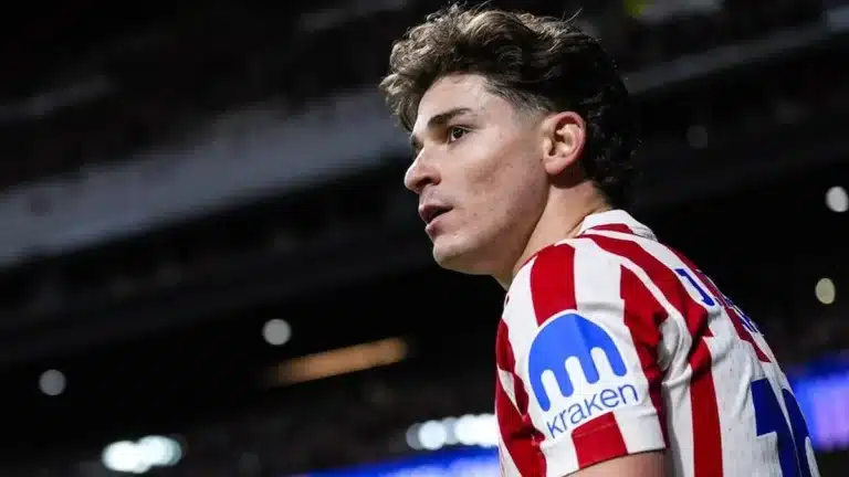 Julián Álvarez, de perfil con la camiseta del Atlético, mira hacia la grada durante un partido nocturno