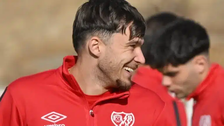 Andrei Rațiu sonriendo durante un entrenamiento del Rayo Vallecano con la equipación roja Umbro