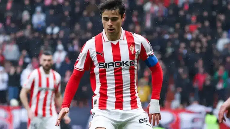 César Gelabert corre con el balón, camiseta rojiblanca del Sporting de Gijón, bajo la lluvia