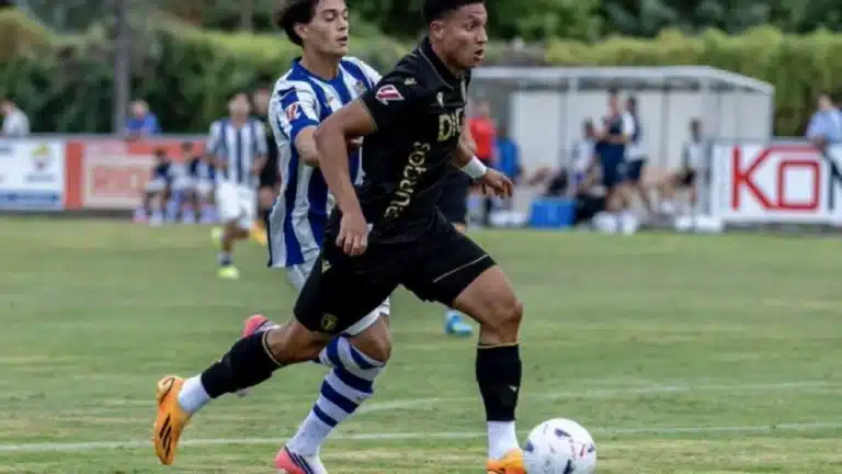Mateo Mejía conduce el balón con la camiseta negra del Burgos CF perseguido por un rival de la Real Sociedad B