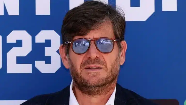 Mateu Alemany con gafas de sol y traje oscuro posa ante un fondo publicitario azul