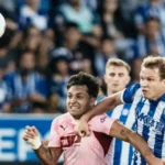 Jugador del Valencia con la camiseta rosa disputa un balón aéreo con un defensor del Alavés