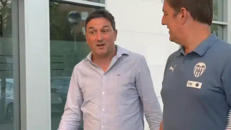 Braulio Vázquez, con camisa de cuadros, conversa y gesticula con un miembro del cuerpo técnico del Valencia CF