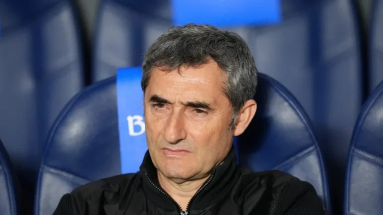 Ernesto Valverde, con gesto serio, sentado en un banquillo de asientos azules con chaqueta negra