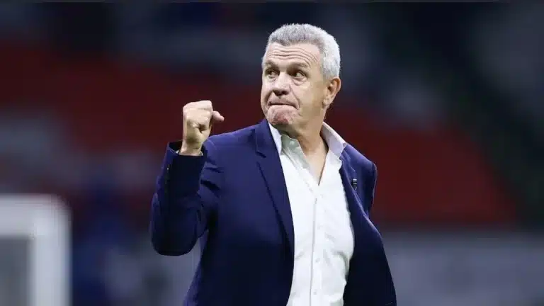 Javier Aguirre celebra con el puño cerrado, en traje azul marino y camisa blanca, desde la banda de un estadio