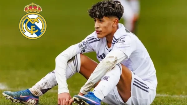 JJ Gabriel sentado en el césped con las rodillas embarradas y el escudo del Real Madrid superpuesto