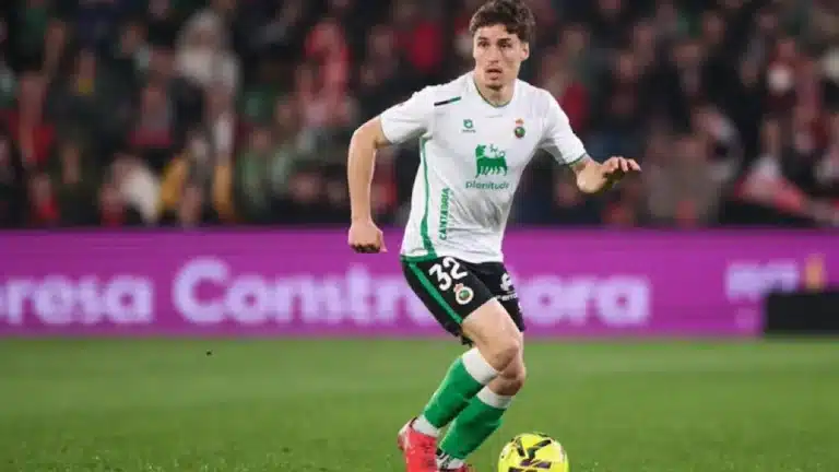 Jorge Salinas conduce el balón con la camiseta blanca del Racing de Santander, número 32, en un partido nocturno